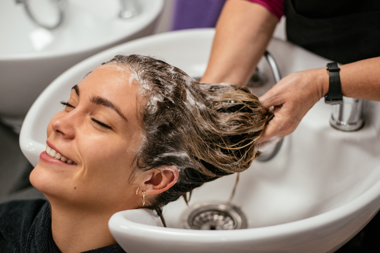 Devojka uklanja balzam sa kose u frizerskom salonu